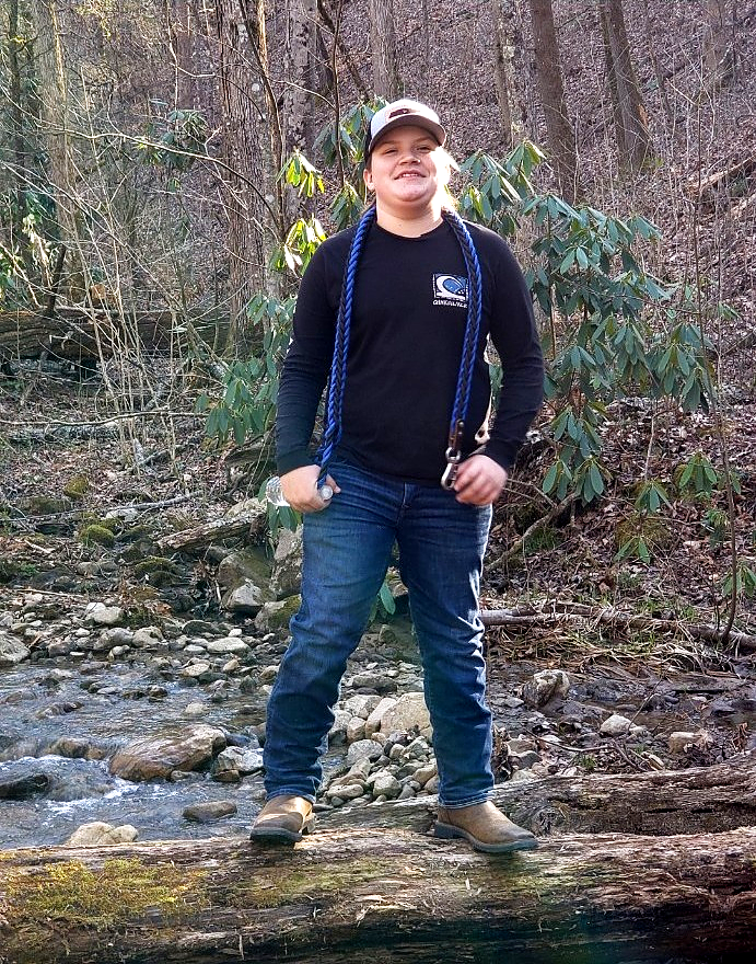 Ayden standing outdoors beside a woodland creek